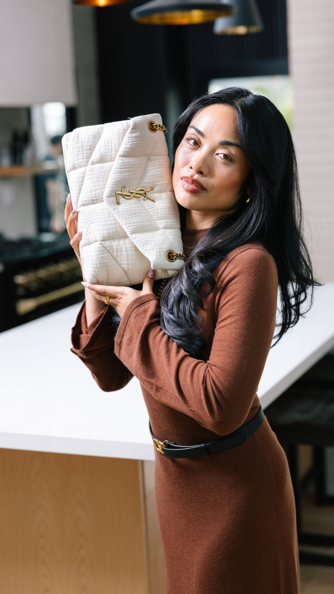 Woman in a designer brown dress holding an Authentic YSL Handbag